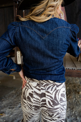 Person wearing a blue denim jacket and zebra print pants with a blurred background