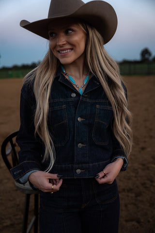 Woman wearing a cowboy hat and denim jacket in an outdoor setting