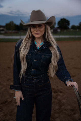 Woman in cowboy hat and denim outfit standing in a field