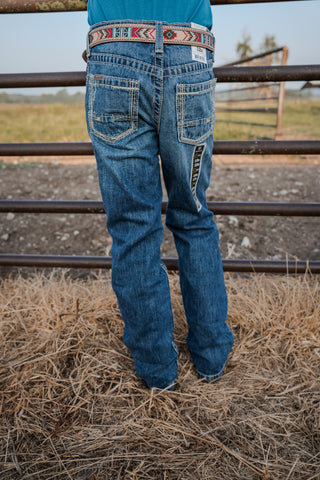 Person wearing blue jeans standing in a field with a fence in the background