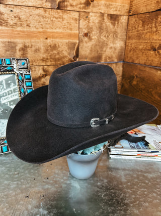 Black cowboy hat on a stand with a wooden background