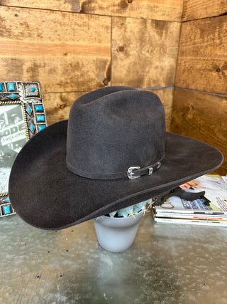 Dark gray saddle on a wooden floor with a magazine underneath