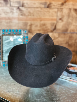 Dark gray cowboy hat on a reflective surface with a wooden background