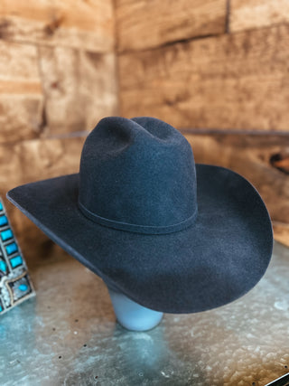 Dark blue cowboy hat on a mannequin head against a wooden background