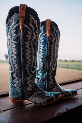 Blue and white cowboy boots with intricate designs on a wooden surface.