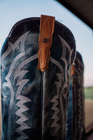 Close-up of a saddle with intricate pattern and leather strap, outdoors.