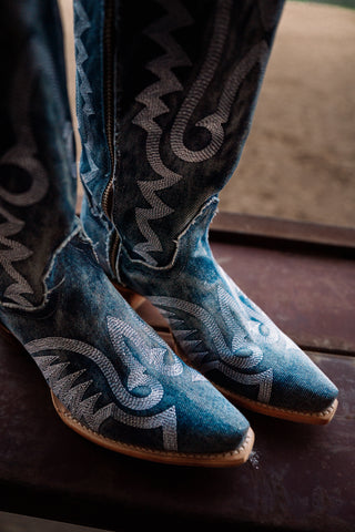 Blue cowboy boots with intricate patterns on a dark surface
