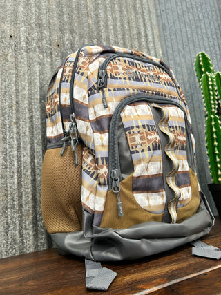 Patterned backpack on a textured surface with a plant in the background