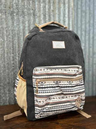Black backpack with patterned front pocket on a wooden surface