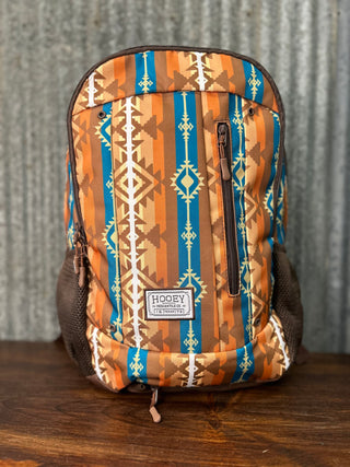 Backpack with tribal pattern on a wooden surface and metal wall background