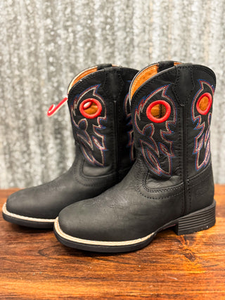 Black cowboy boots with red accents on a wooden surface and textured gray background