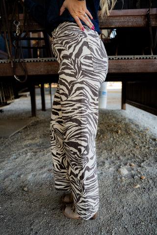 Person wearing zebra print pants in an indoor setting with wooden beams.