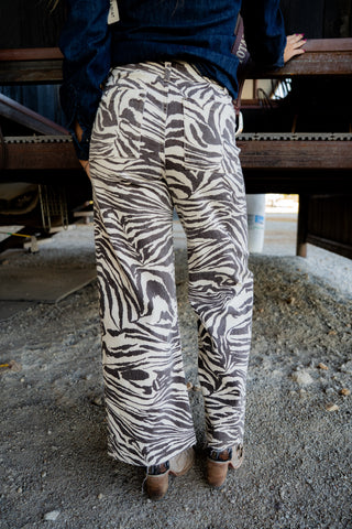Person wearing zebra print pants standing on a concrete floor.