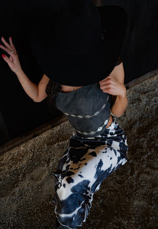 Person wearing a black top and tie-dye pants on a dark background