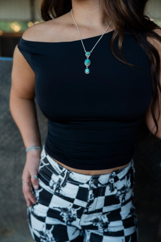Person wearing a black top and checkered pants with a blurred background