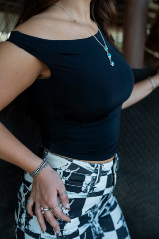 Person wearing a black top and patterned pants with a blurred background