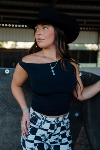 Woman wearing a black top and checkered pants with a blurred background