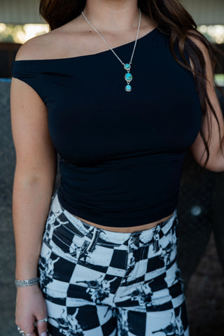 Person wearing a black top and checkered pants with a blurred background