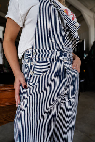 Person wearing a black and white striped apron over a white shirt.