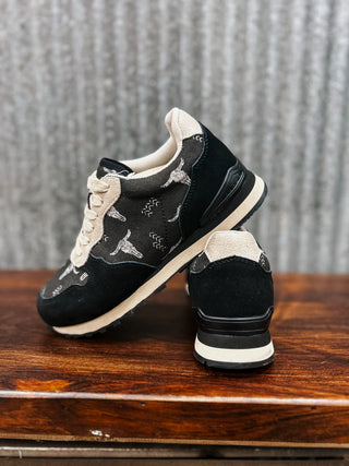 Black and white sneakers on a wooden surface with a textured gray background