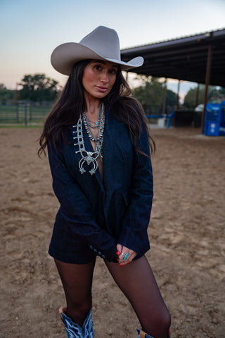 Woman in cowboy hat and boots standing in a dirt arena