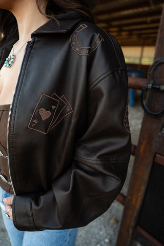 Black leather jacket with heart and card design on a blurred background