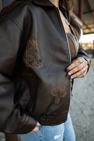 Brown leather jacket with embroidered designs on a blurred background