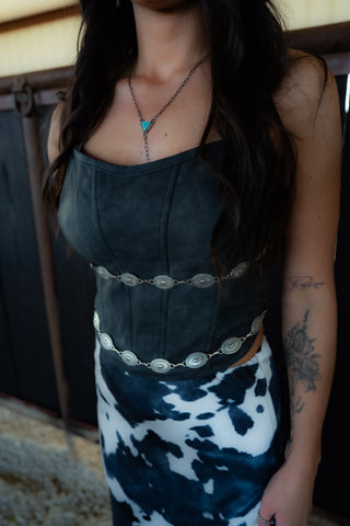 Person wearing a dark green top with a patterned skirt indoors