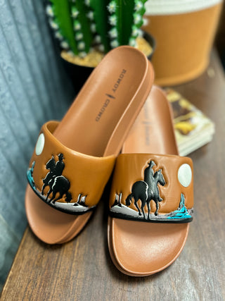 Pair of brown sandals with horse designs on a wooden surface.