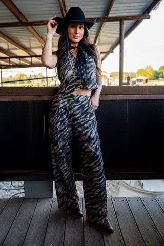 Woman in a zebra print outfit standing on a wooden deck.