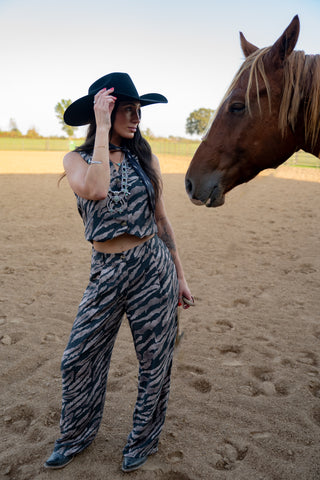 Woman in zebra print outfit with a horse on a sandy background