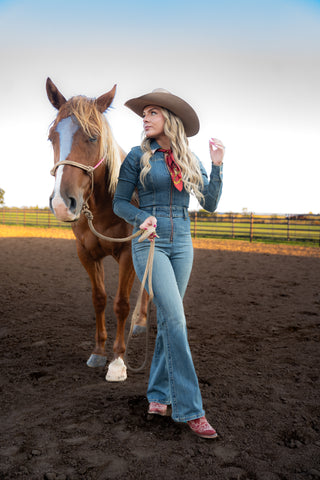 Woman in a denim outfit with a horse in an outdoor setting