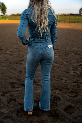 Person wearing a blue denim outfit standing on a dirt field.