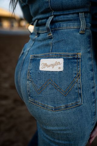 Close-up of blue jeans with Wrangler logo on pocket, blurred background
