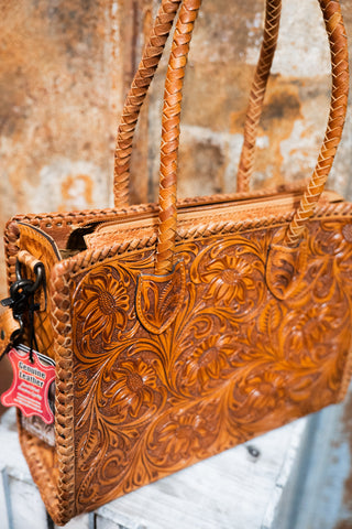 Brown leather handbag with intricate patterns on a textured surface