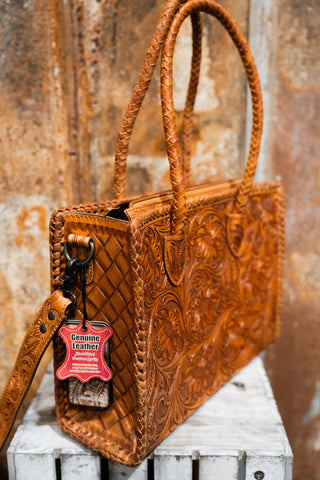 Brown leather handbag with intricate patterns on a wooden surface