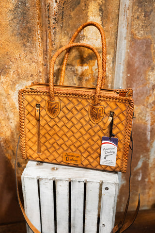 Brown woven handbag on a white wooden crate with a textured brown background