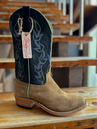 Brown cowboy boot with black interior on a wooden surface