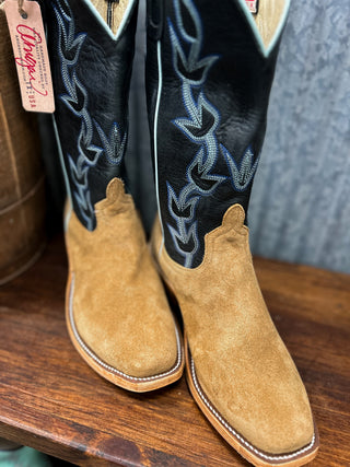 Pair of cowboy boots with intricate black and blue embroidery on a wooden surface.