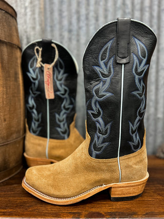 Pair of tan and black cowboy boots with intricate designs on a wooden surface.