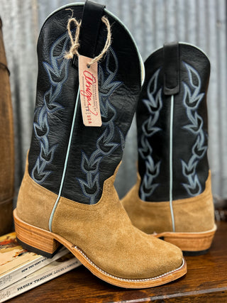 Pair of tan and black cowboy boots with a brand tag on a wooden surface.