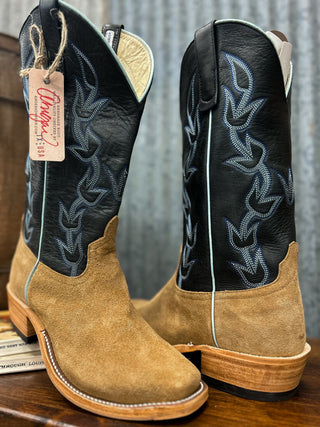 Pair of black and brown cowboy boots with a visible brand tag on a wooden surface.
