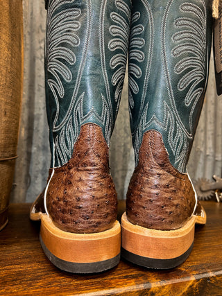 Close-up of a pair of cowboy boots with detailed design on the leg and wooden sole.