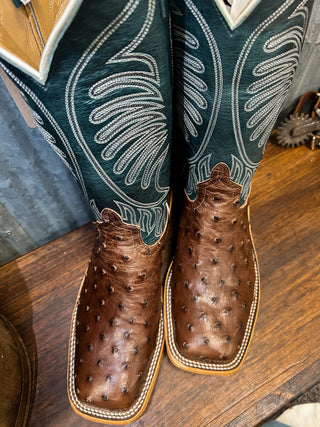Close-up of brown leather boots with detailed stitching on a wooden surface