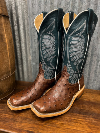 Pair of brown cowboy boots with black and white patterned tops on a wooden surface.