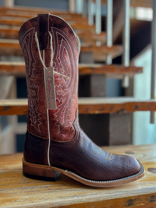 Brown cowboy boot with intricate design on a wooden surface