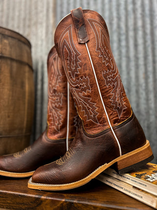 Brown cowboy boots with intricate designs on a wooden surface and metal wall background