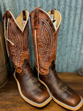 Pair of brown cowboy boots with intricate designs on a wooden surface.