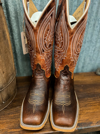 Pair of brown cowboy boots with intricate designs on a wooden surface.