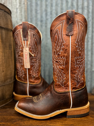 Brown cowboy boots with intricate designs on a wooden surface.